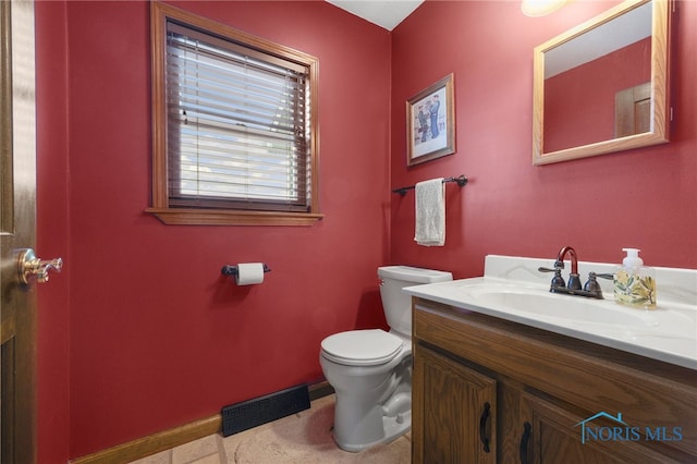 half bathroom with toilet, vanity, visible vents, and baseboards