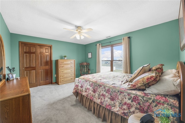 carpeted bedroom featuring visible vents, ceiling fan, and a textured ceiling