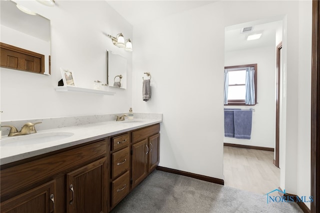 bathroom with double vanity, baseboards, visible vents, and a sink