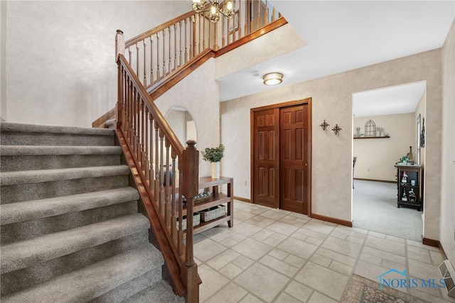 foyer entrance with stone tile floors, baseboards, arched walkways, stairway, and a notable chandelier