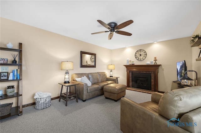 living area with a brick fireplace, carpet, baseboards, and a ceiling fan