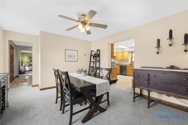 dining space with a ceiling fan, light carpet, baseboards, and light tile patterned floors