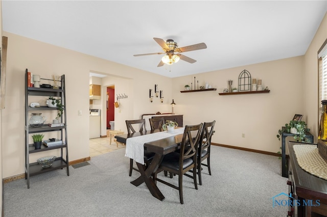 dining area featuring baseboards, washer / clothes dryer, a ceiling fan, and light colored carpet