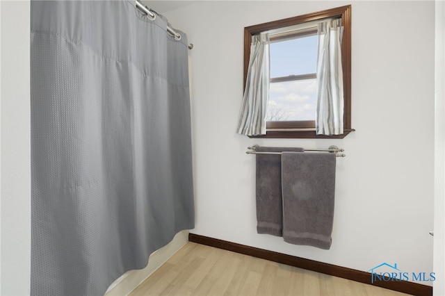 bathroom featuring curtained shower, wood finished floors, and baseboards