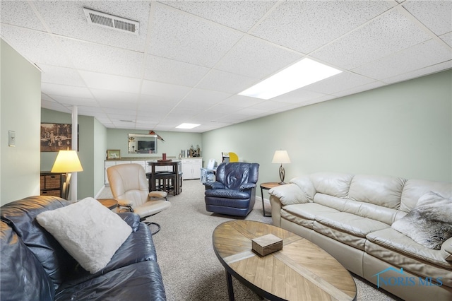 carpeted living area with a paneled ceiling, baseboards, and visible vents