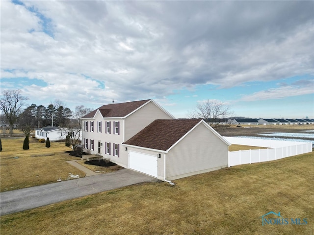 view of property exterior featuring a garage, fence, aphalt driveway, and a lawn