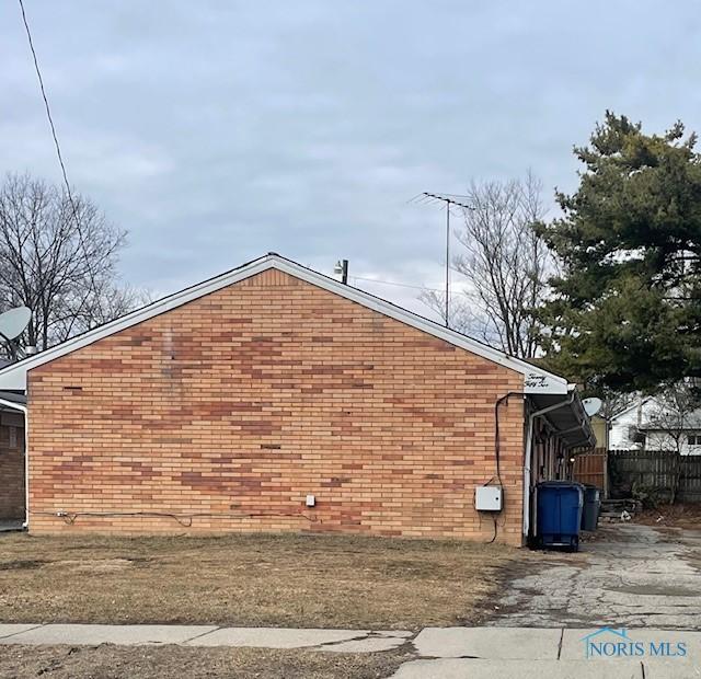 view of side of home featuring fence and brick siding