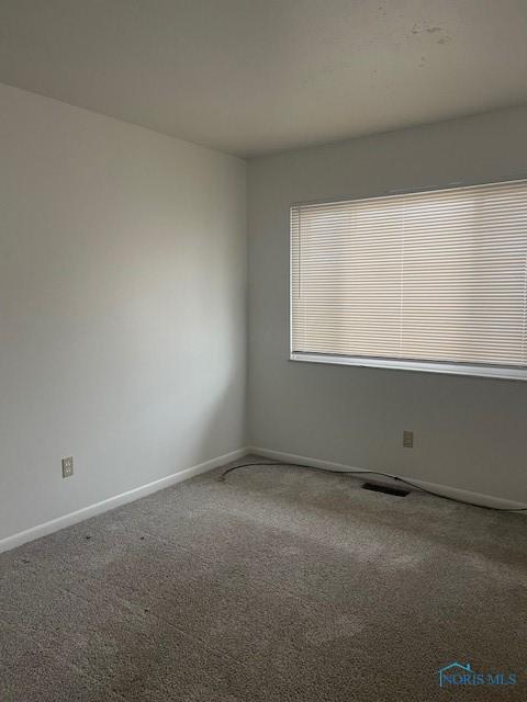 carpeted spare room with visible vents and baseboards