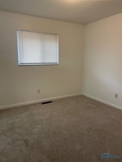 carpeted empty room featuring visible vents and baseboards