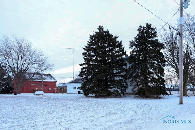 yard covered in snow with an outbuilding and a barn