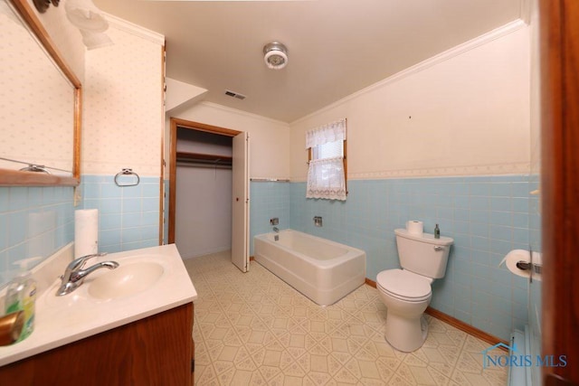 bathroom with a bath, toilet, a wainscoted wall, and visible vents