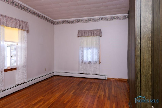 unfurnished room with ornamental molding, baseboard heating, wood-type flooring, and baseboards