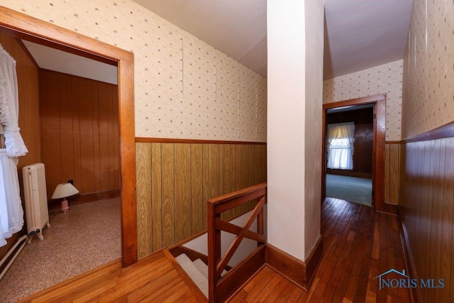 hallway with radiator, wainscoting, an upstairs landing, hardwood / wood-style floors, and wallpapered walls