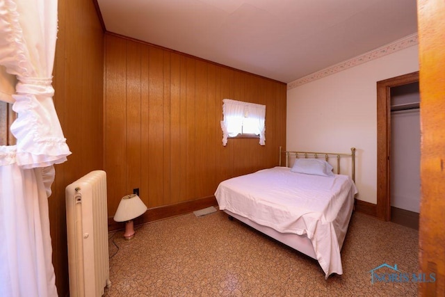 bedroom with wood walls, radiator heating unit, and baseboards