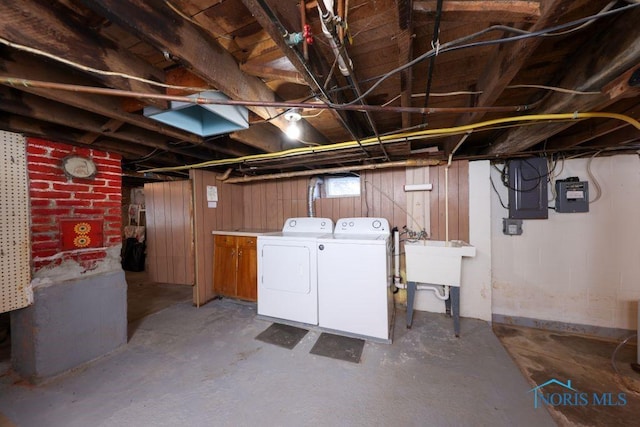 below grade area with washing machine and clothes dryer, electric panel, and wooden walls