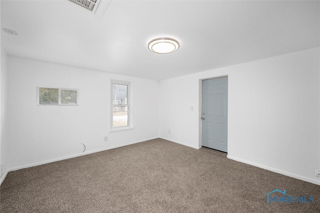 spare room with carpet floors, visible vents, and baseboards