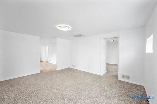 carpeted empty room featuring visible vents and baseboards