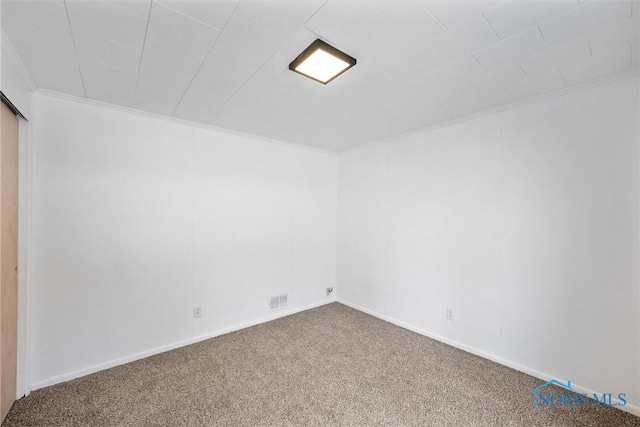 unfurnished room featuring ornamental molding, carpet flooring, visible vents, and baseboards