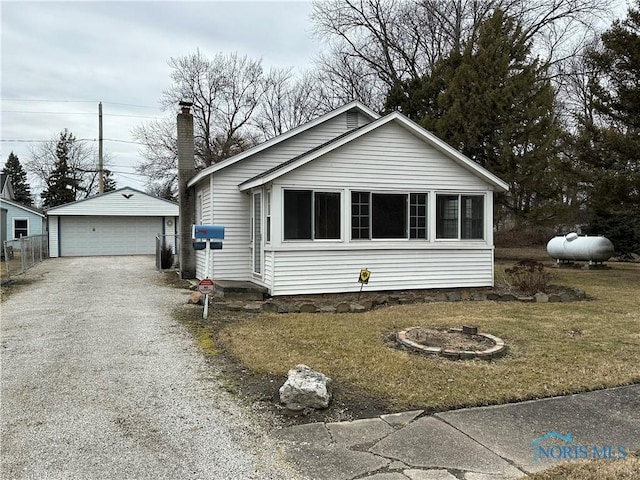 view of front facade featuring a detached garage, an outbuilding, a chimney, and a front yard