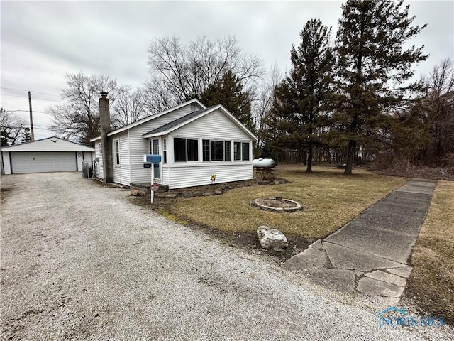 view of front of house with an outbuilding, a chimney, a detached garage, and a front yard