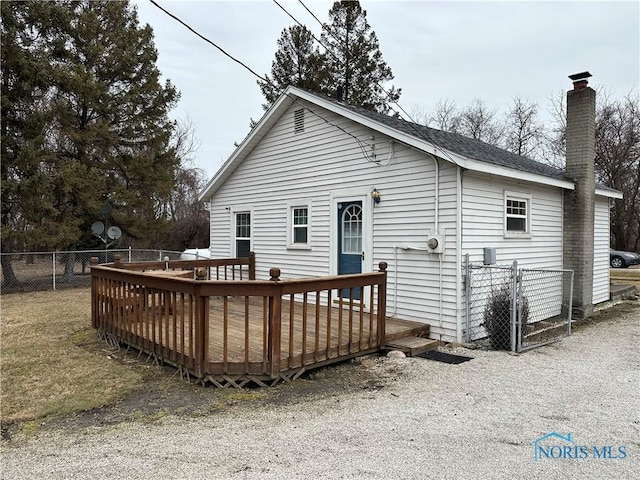 back of house featuring a chimney, a deck, and fence