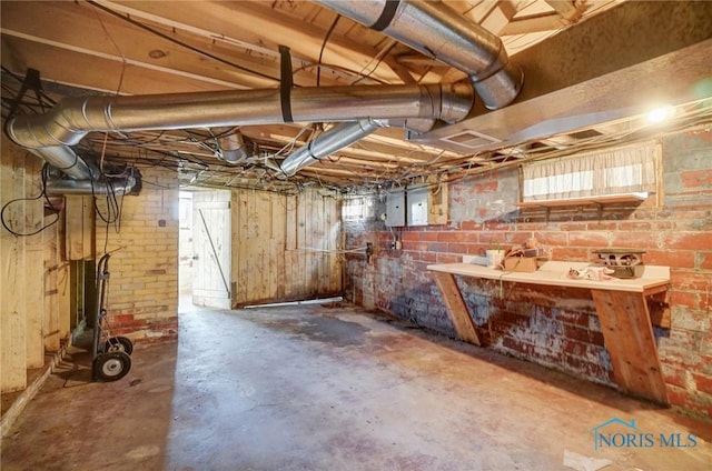 below grade area featuring electric panel and brick wall