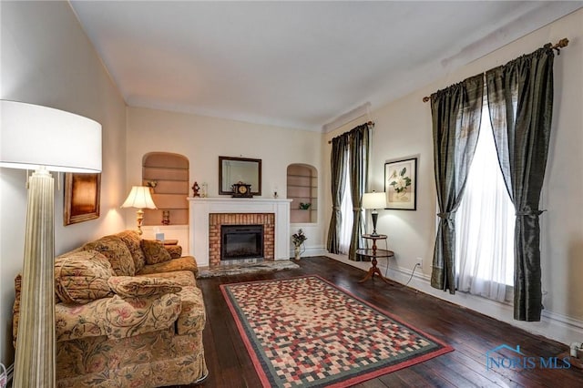 living room with baseboards, hardwood / wood-style flooring, and a fireplace