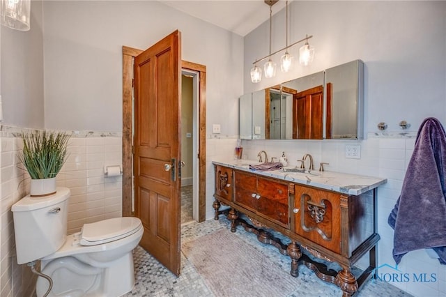 bathroom with tile patterned flooring, tile walls, toilet, and vanity