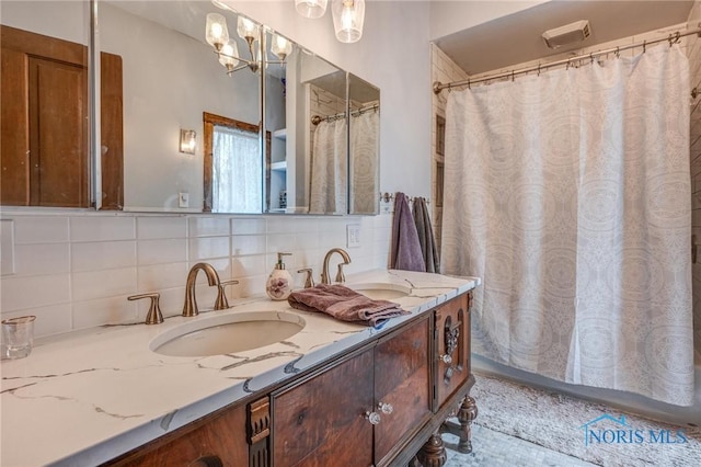 bathroom with double vanity, an inviting chandelier, a sink, and tasteful backsplash