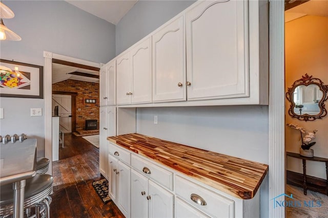 kitchen featuring butcher block countertops, white cabinetry, and dark wood-type flooring