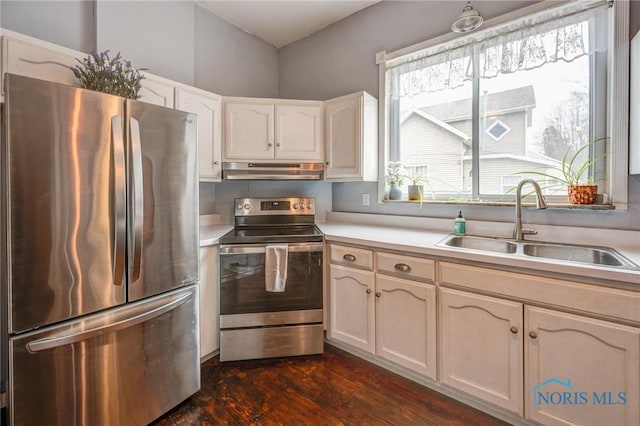 kitchen featuring a sink, under cabinet range hood, light countertops, appliances with stainless steel finishes, and dark wood-style flooring