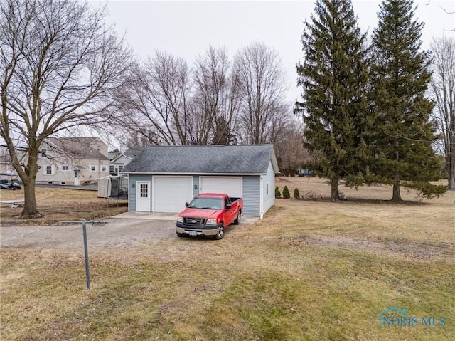 view of front facade with a detached garage, an outbuilding, and a front lawn