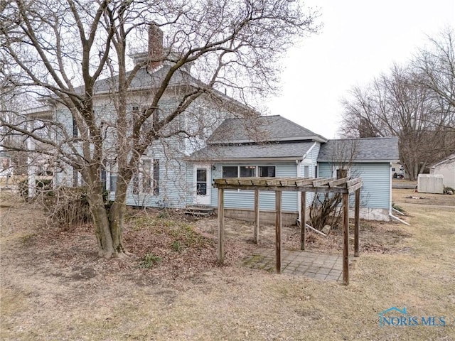 back of property with a pergola and a shingled roof