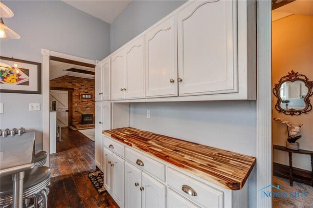 kitchen featuring white cabinetry, wood counters, and vaulted ceiling