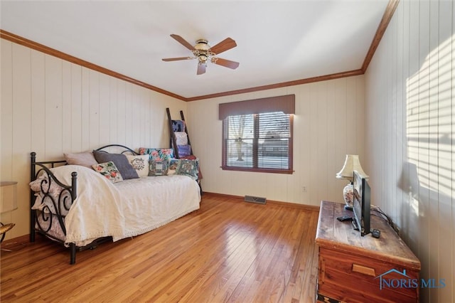 bedroom with ornamental molding, visible vents, light wood finished floors, and a ceiling fan