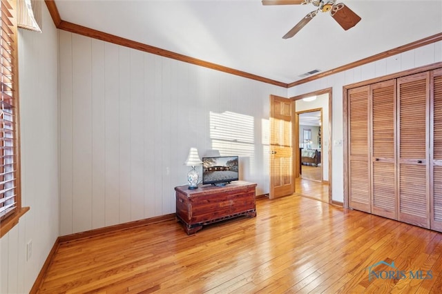 bedroom with crown molding, a closet, visible vents, light wood-style flooring, and baseboards