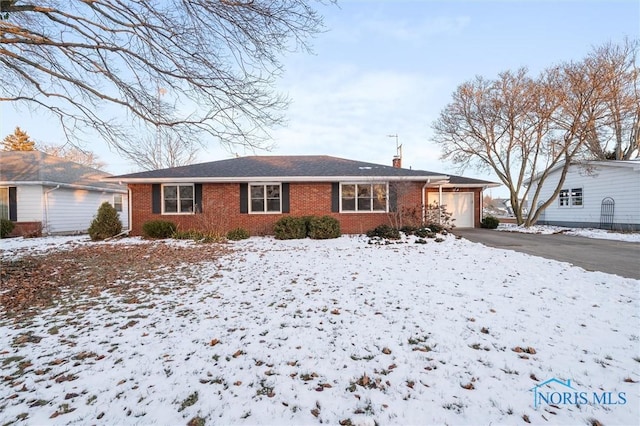 ranch-style home with a garage, driveway, brick siding, and a chimney