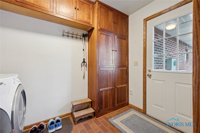 washroom with cabinet space, baseboards, brick floor, and independent washer and dryer