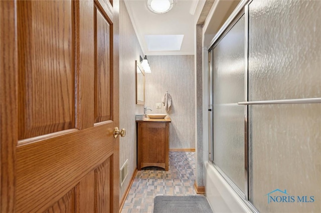 bathroom with a skylight, crown molding, bath / shower combo with glass door, visible vents, and vanity