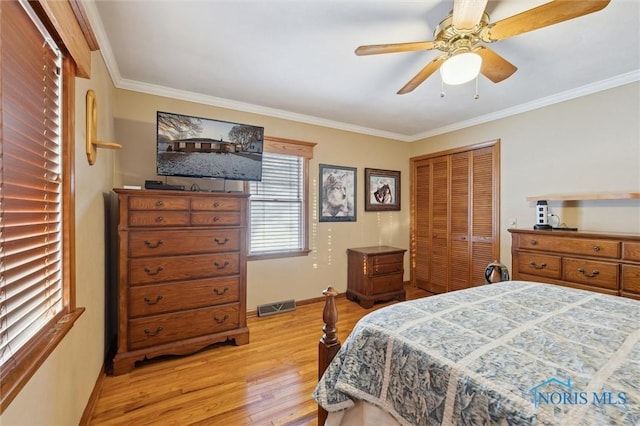 bedroom featuring baseboards, visible vents, crown molding, light wood-type flooring, and a closet