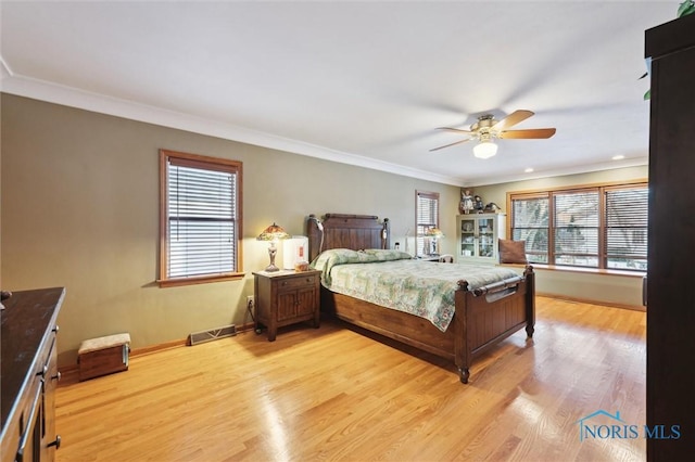 bedroom with light wood-type flooring, multiple windows, visible vents, and ornamental molding