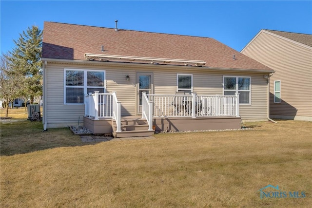 back of property featuring roof with shingles and a yard