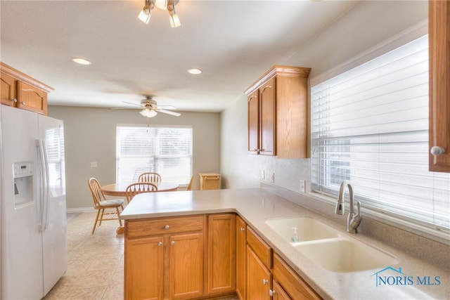 kitchen featuring white fridge with ice dispenser, light countertops, a sink, and a peninsula