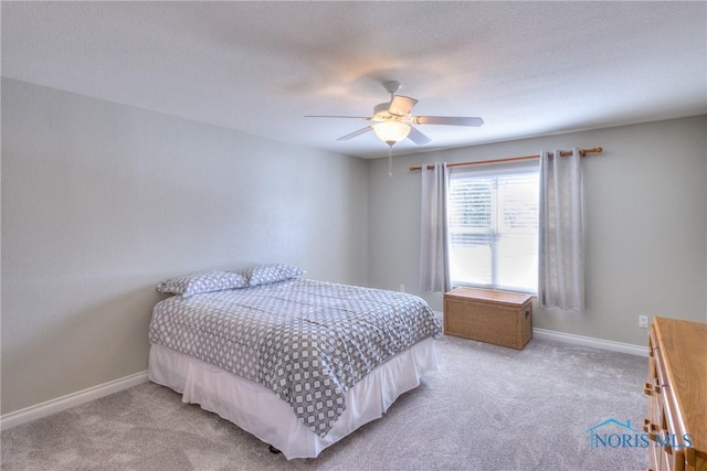 carpeted bedroom with ceiling fan, a textured ceiling, and baseboards