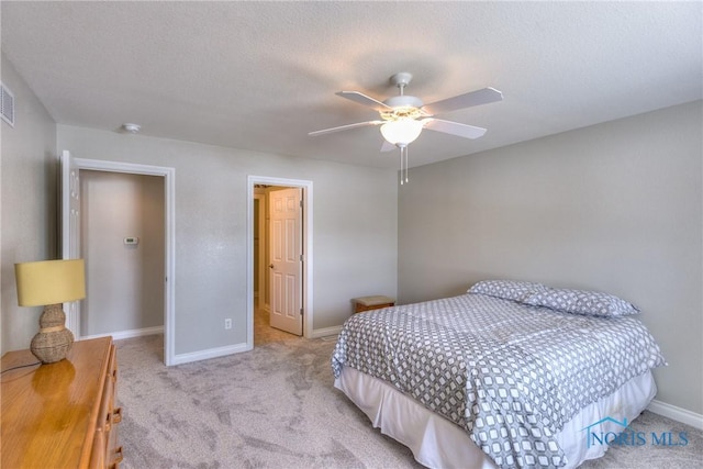 bedroom featuring light carpet, a ceiling fan, baseboards, and a textured ceiling