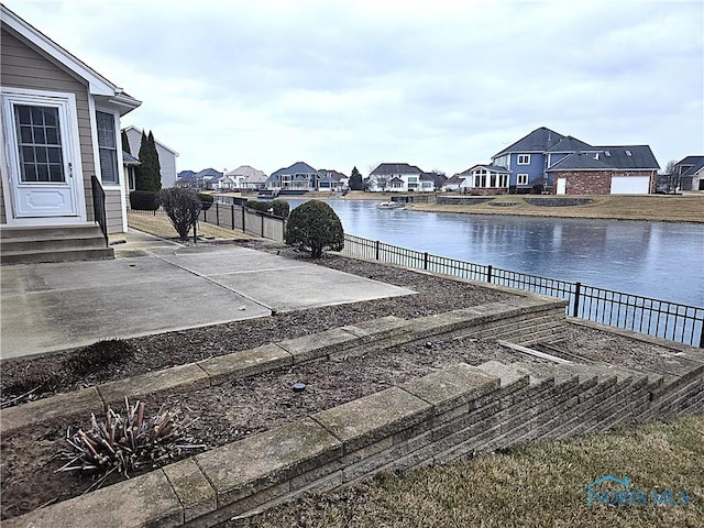 exterior space with entry steps, a water view, fence, a residential view, and a patio area