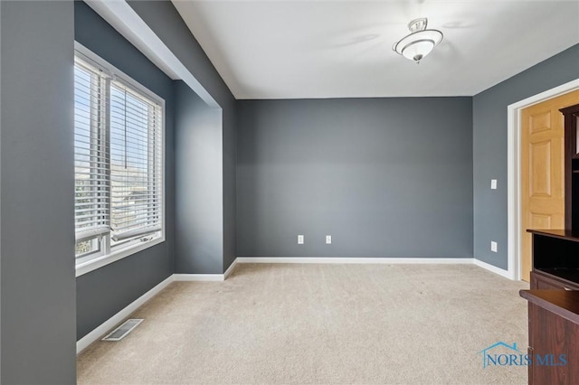 carpeted spare room featuring visible vents and baseboards