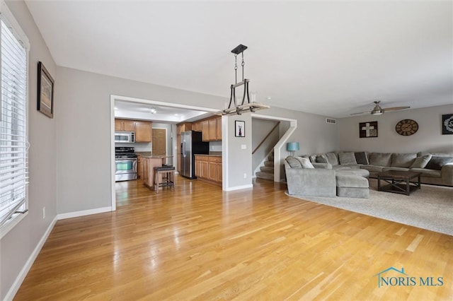 living room with baseboards, stairway, visible vents, and light wood-style floors