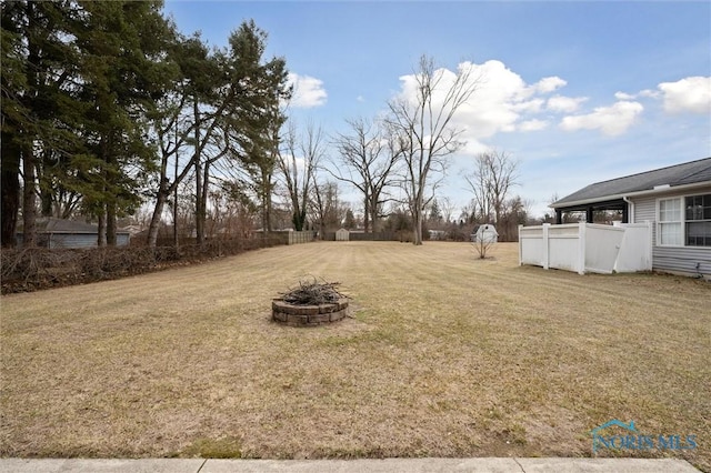 view of yard with an outdoor fire pit and fence