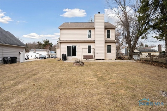 rear view of property featuring entry steps, a lawn, a chimney, and fence